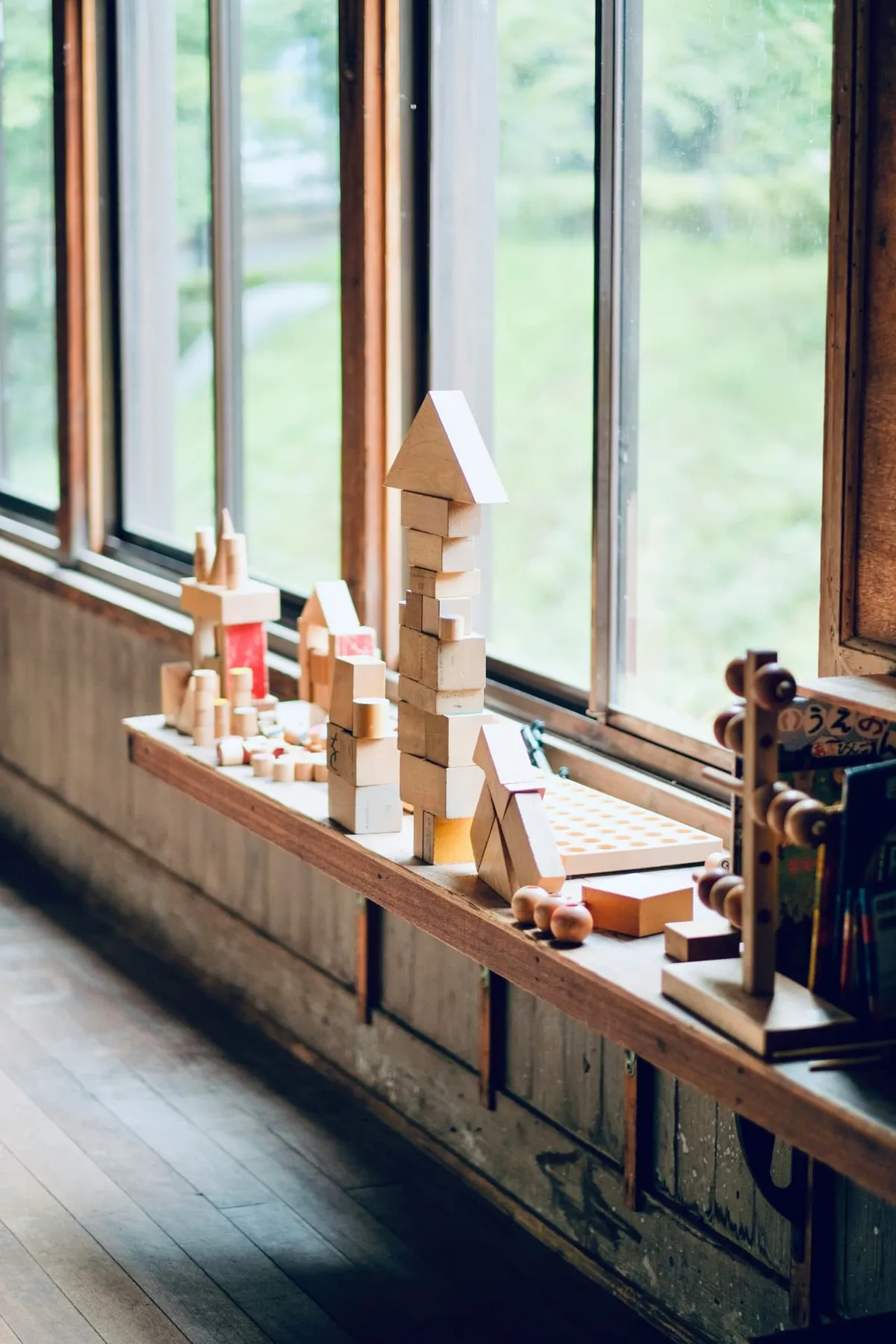 Wooden building blocks arranged along a classroom windowsill in natural light.