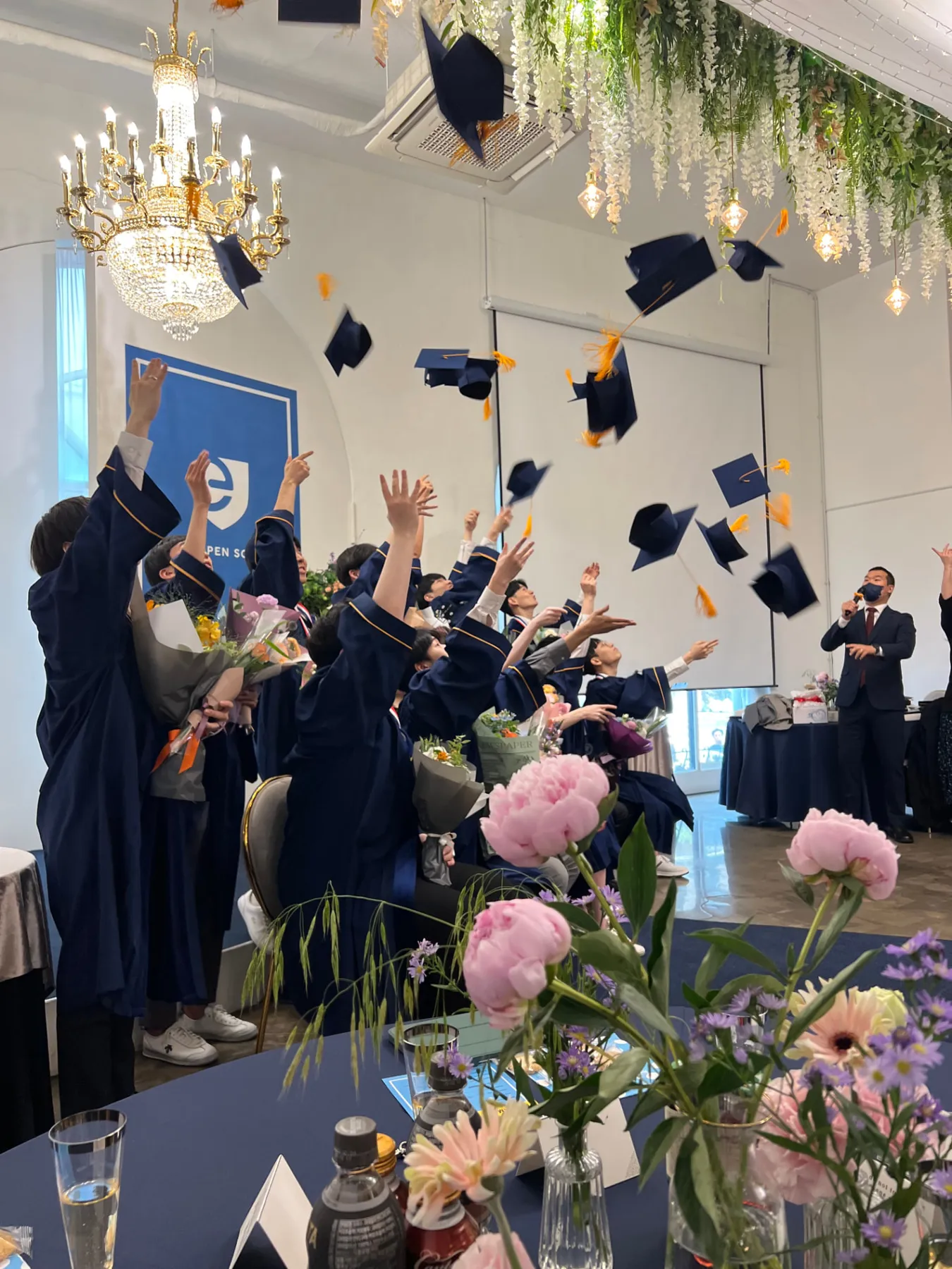 EOS graduates celebrating at commencement, caps in the air.